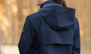 Granatowy płaszcz jeździecki z kapturem i perforowanym napisem "COVALIERO" na plecach.